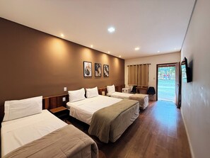 Habitación de hotel con tres camas, un escritorio y una televisión.