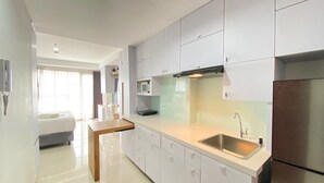 Una cocina moderna con armarios blancos, un lavamanos de acero inoxidable y un microondas integrado.