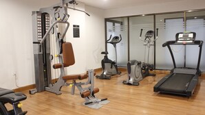 Un gimnasio con máquinas de cardio, máquinas de pesas y una cinta de correr.