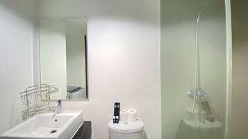 Une salle de bain moderne avec un lavabo blanc, des toilettes et une douche à parois de verre.