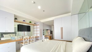 Un dormitorio moderno con una cama grande, un escritorio con televisor de pantalla plana y una kitchenette.