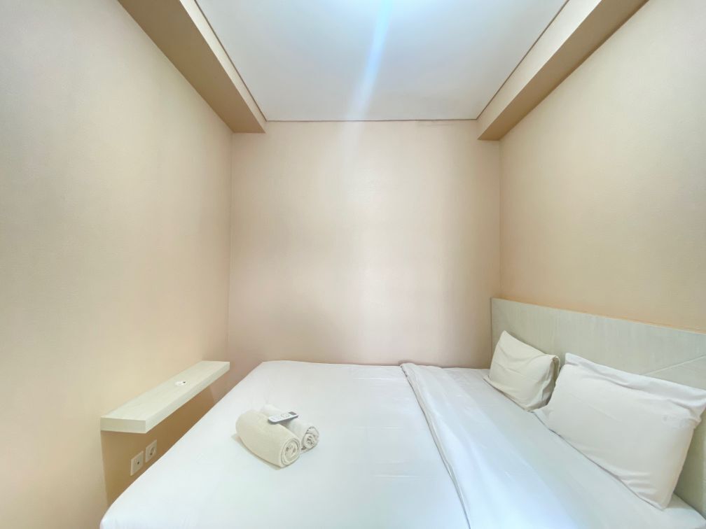 A small, neatly arranged bedroom with a single bed, a nightstand, and a ceiling light.