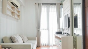 A modern hotel room with a sofa, two small stools, a desk with a computer, and a TV. - Attractive 1BR Apartment at Royal Olive Residence (Jakarta)