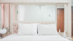 A neatly made bed with white linens, a bedside table with a mirror, and a wall-mounted light fixture. - Attractive 1BR Apartment at Royal Olive Residence (Jakarta)