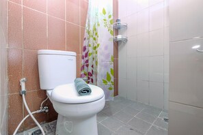 Ein Badezimmer mit Toilette, Duschvorhang und Fliesen.