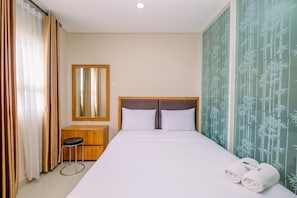 Una habitación de hotel con una cama, una mesita de noche de madera, un espejo y una pared con motivos de bambú.