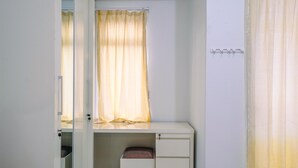 Une pièce avec un bureau blanc, une fenêtre ornée de rideaux jaunes et un mur blanc.