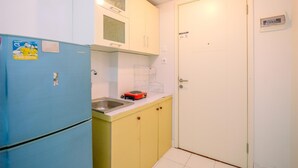 Une cuisine de taille réduite avec un réfrigérateur bleu, des placards jaunes et une porte blanche.
