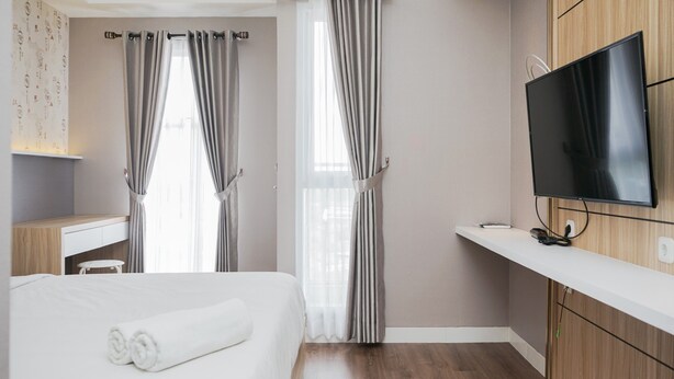 Een hotelkamer met een bed, een bureau, een televisie en een raam met gordijnen.