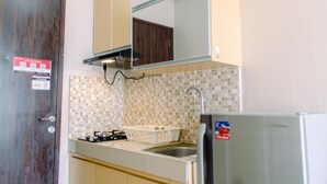 A compact kitchen with a stove, sink, and a refrigerator. - Nice and Comfy Studio Room at Serpong Greenview Apartment (South Tangerang)