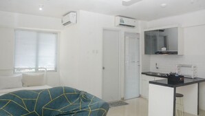 A compact hotel room with a bed, a kitchenette, and a bathroom.