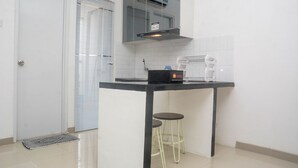 A compact kitchen with a black countertop, a built-in stove, and two stools.