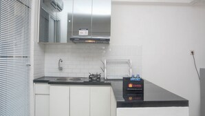 A kitchen with white cabinets, a black countertop, a stainless steel range hood, and a box of travel essentials.