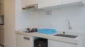 A modern kitchen with white cabinets, a stainless steel sink, and a blue basket on the countertop. - Gorgeous and Comfy Studio Sky House BSD Apartment (Pagedangan)