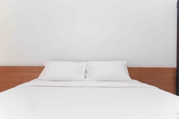 A neatly made bed with white bedding and a wooden headboard.