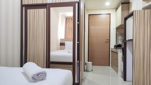 A hotel room with a bed, a bathroom, and a kitchenette.