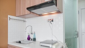A modern kitchen with a stainless steel sink, a built-in oven, and a range hood. - Restful and Tidy 2BR at Green Pramuka City Apartment (Jakarta)