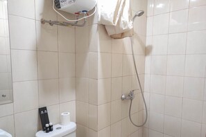 A bathroom with a shower, toilet, and a hairdryer on the wall.