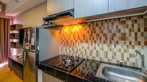 A compact kitchen with a refrigerator, stove, and sink. - Cozy Living and Homey Studio Apartment at Margonda Residence 5 (Depok)