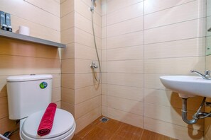Bathroom features a shower area, toilet, and sink with a chrome faucet.