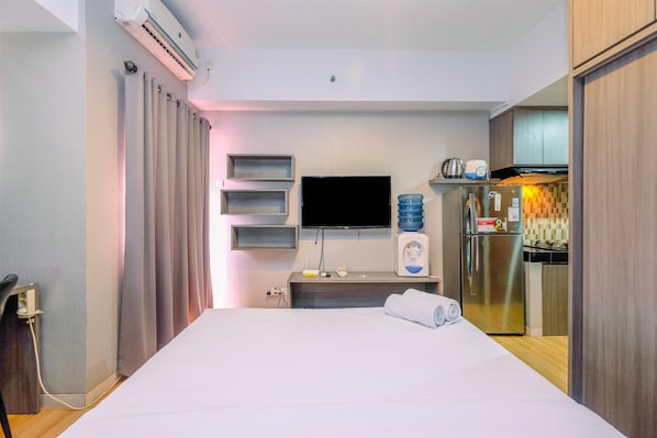 Une chambre d’hôtel équipée d’un lit, d’une télévision à écran plat, d’un minibar, d’un réfrigérateur et d’une petite kitchenette.