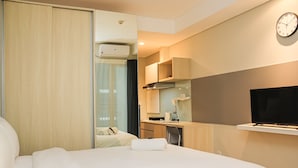 Una habitación de hotel con una cama, un escritorio, un televisor y un reloj en la pared.