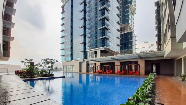Un hotel moderno con piscina, edificios altos y una zona de estar techada.