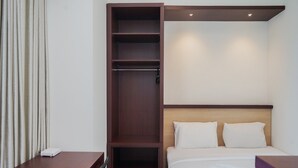 A hotel room with a bed, a wooden wardrobe, a desk, and a chair. - Comfy and Nice Studio at Tree Park City BSD Apartment (South Tangerang)