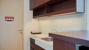 A modern kitchen with wooden cabinets, a white countertop, and a stainless steel sink. - Comfy and Nice Studio at Tree Park City BSD Apartment (South Tangerang)