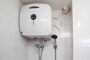 A white, wall-mounted water heater with a control knob, two water outlets, and a handheld showerhead.