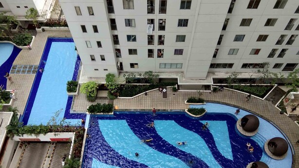 A rooftop swimming pool with multiple lanes and a circular area with seating. - Simple and Cozy Living Studio Room at Bassura City Apartment (Jakarta)