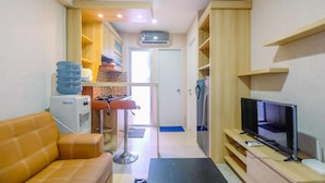 A compact living space with a sofa, a TV, a kitchenette, and a bathroom. - Nice and Strategic 2BR at Bassura City Apartment (Jakarta)