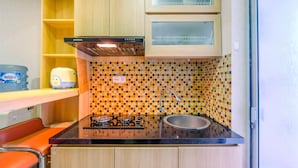 A compact kitchen with a gas stove, sink, and wooden cabinets. - Nice and Strategic 2BR at Bassura City Apartment (Jakarta)