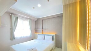 A hotel room with a large bed, a bedside table, a wall-mounted shelf, and a window with curtains.