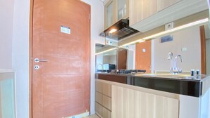 A modern kitchen with a wooden door, a stainless steel sink, and a built-in oven.