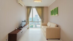 Una sala de estar moderna con un sofá, un televisor de pantalla plana, un mueble bajo y un amplio ventanal con cortinas.