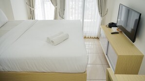 A hotel room with a bed, a TV on a wooden stand, and curtains.