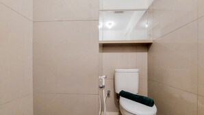 A bathroom with a toilet, a shower, and a mirror. - Nice and Cozy Studio at Baileys Apartment (South Tangerang)