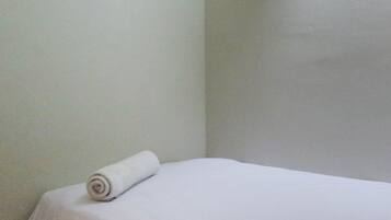 A neatly made bed with a rolled white towel on the side.