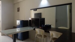 A compact kitchen with a glass-top table, two chairs, a refrigerator, and a microwave. - Best Deal 2BR Apartment at Dian Regency near ITS (Surabaya)
