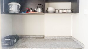 A kitchen with a stove, kettle, and tea set on shelves. - Best Deal 2BR Apartment at Dian Regency near ITS (Surabaya)