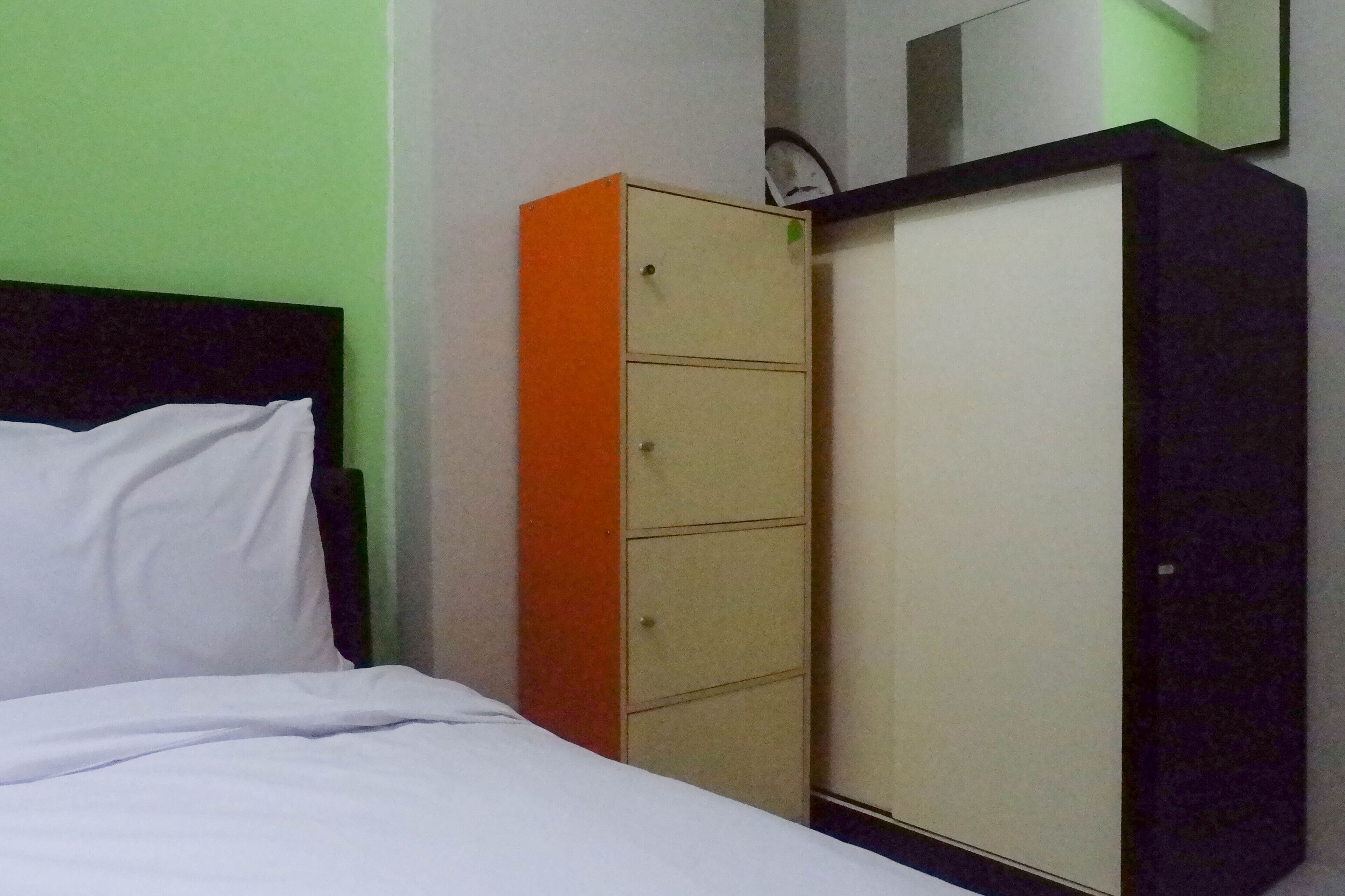 A room with a bed, a wardrobe with two doors, and a clock on the wall.