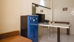 A compact room with a blue refrigerator, a small table, and a chair. - Best Deal 2BR Apartment at Dian Regency near ITS (Surabaya)