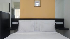 A neatly made bed with white linens, a black headboard, and a single framed picture on the wall above. - Best Deal 2BR Apartment at Dian Regency near ITS (Surabaya)