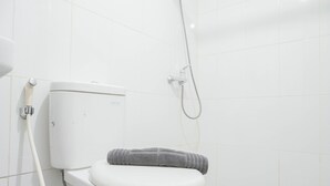A white toilet with a towel on it, a shower head, and a toilet paper holder.