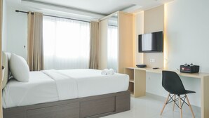 A modern hotel room with a large bed, a desk with a chair, a flat-screen TV, and a bathroom visible through the window.