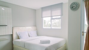 Un lit bien fait, avec du linge de lit blanc, une table de chevet, une horloge au mur et une fenêtre avec des rideaux.