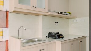 Une cuisine de taille réduite, équipée d’un évier, d’une cuisinière et de placards.