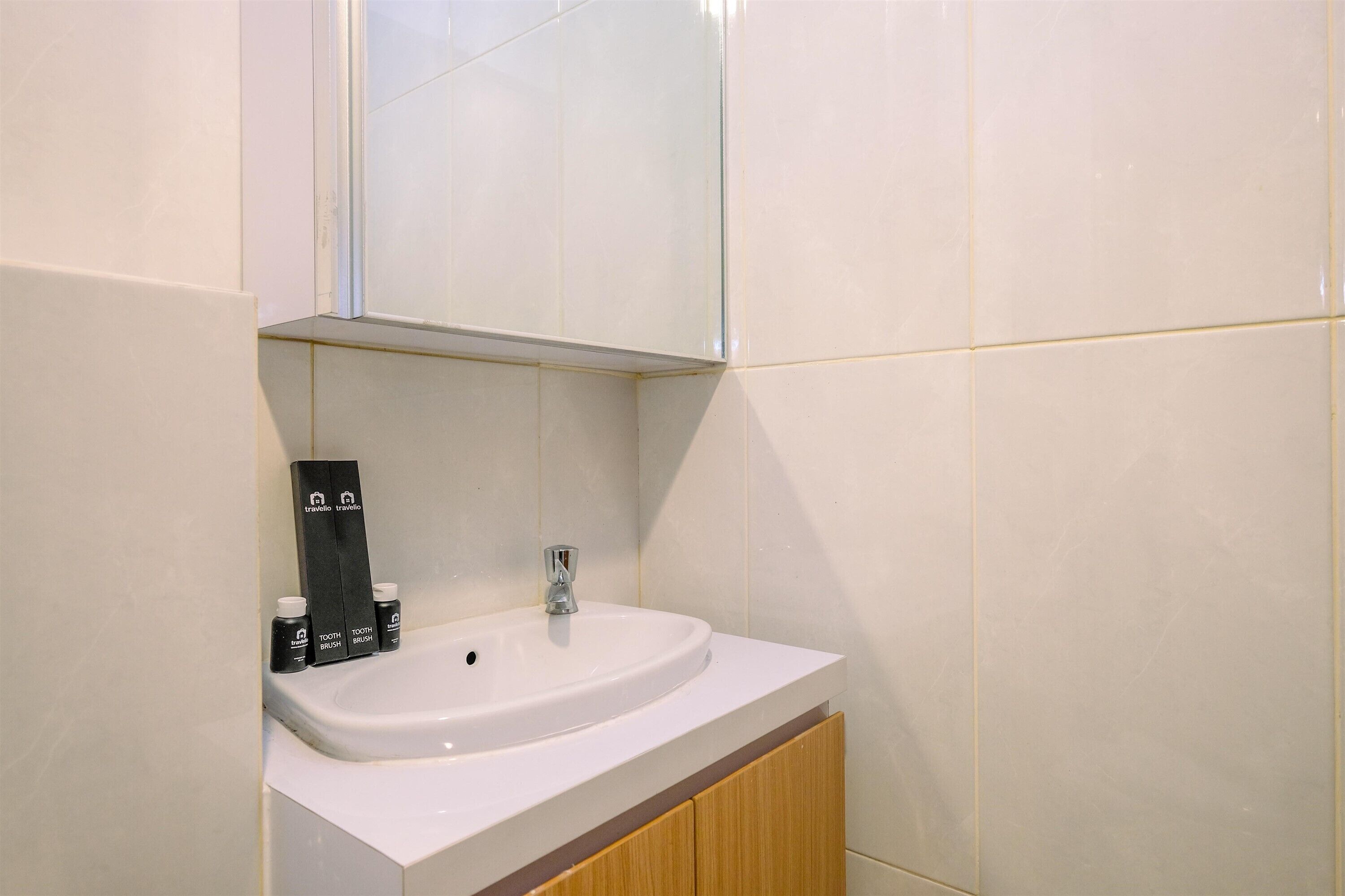 Une salle de bain avec un lavabo blanc, un miroir au-dessus et des articles de toilette posés sur le comptoir.