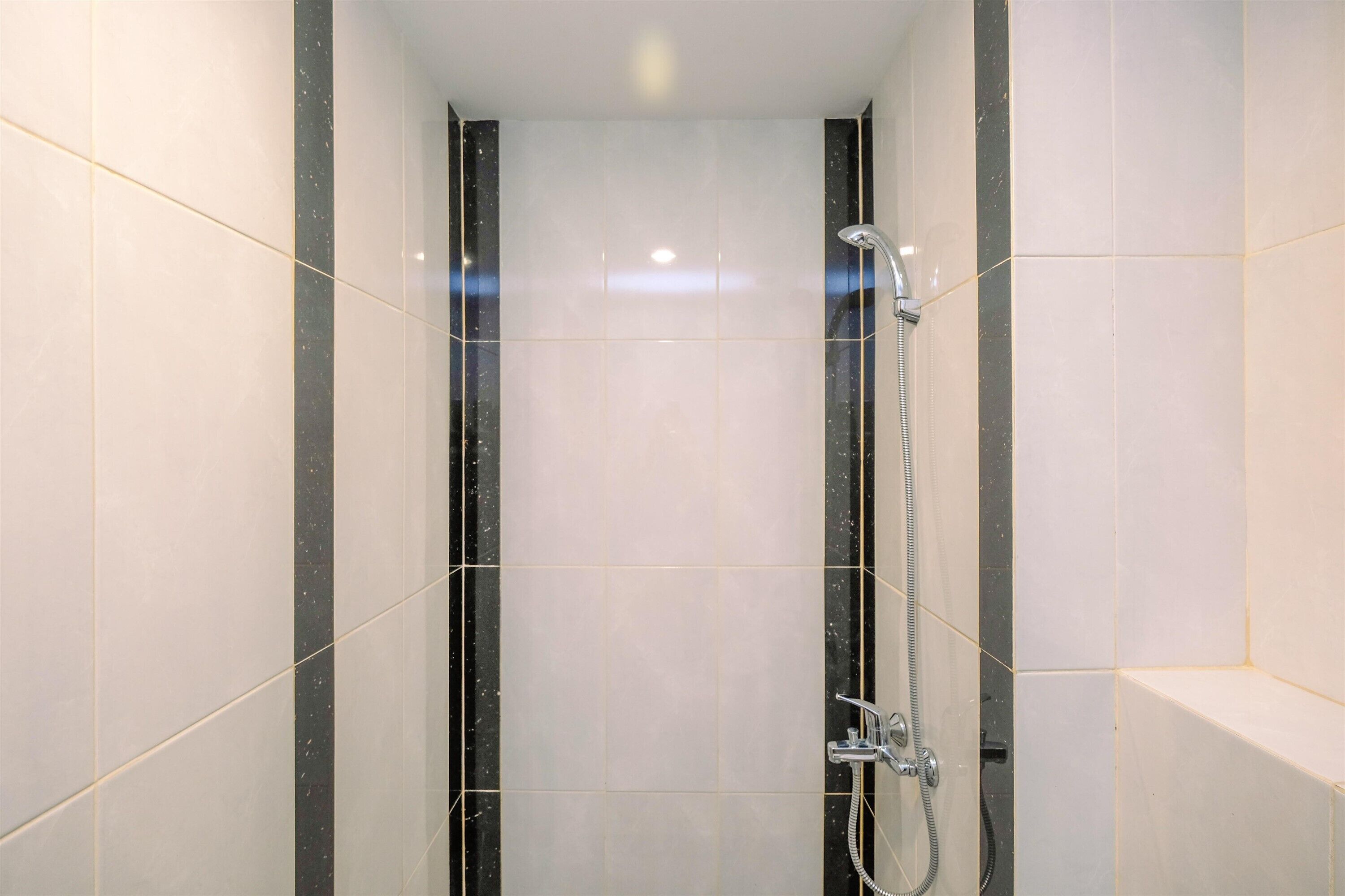 A modern shower with a handheld showerhead and a wall-mounted faucet.